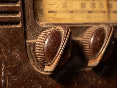 Macro close-up vintage radio knobs, aged bakelite texture, rusted pointer, abstract dial markings, ultra-realistic vintage product shot.