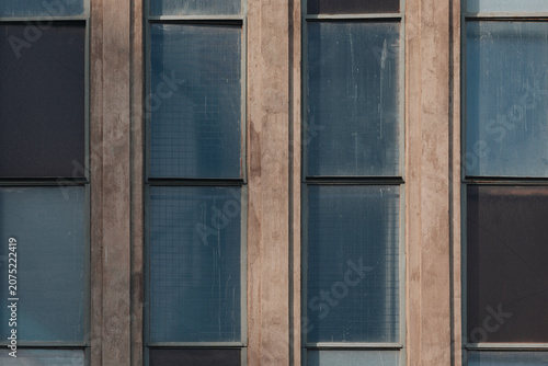 Repetitive blue glass windows on a concrete urban building facade