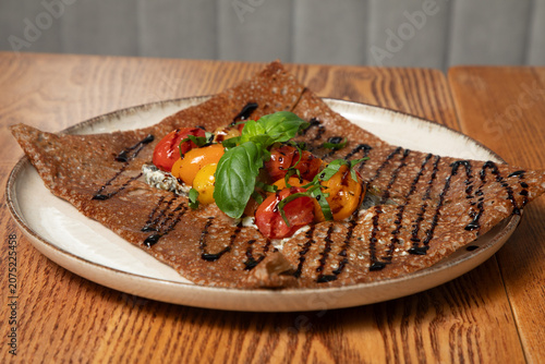Tableau sur toile Préparation de crêpes bretonnes avec des légumes sur une assiette en bois