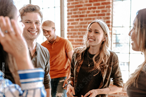 Tableau sur toile Group of people smiling and chatting in a casual setting with brick walls and windows