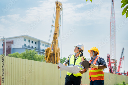 Photos Civil engineers analyzing blueprints at a construction site