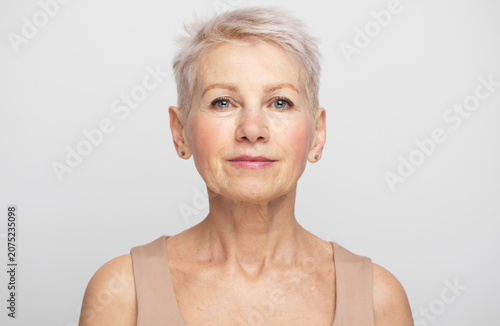 Beauty portrait of an eldelry woman with short silver hair on a clean neutral background, natural and elegant.