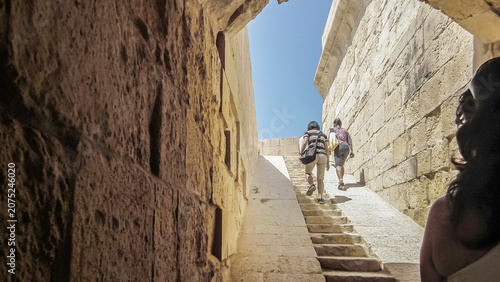 Visitors climb the steps onto the walls of St John Bastion fortress courtyard in Vittoriosa Birgu city in Malta.