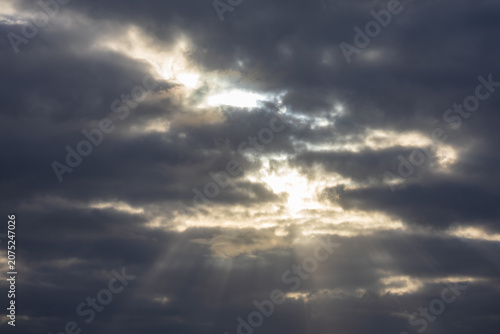 Canvas Print Dramatic crepuscular sunbeams breaking through dark moody storm clouds over the