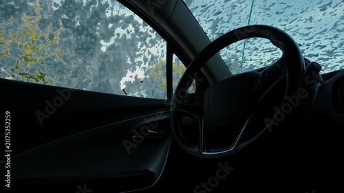 Driver-side cabin seen from inside as foam streaks cover the windshield and side window. Washing a car on the street. Clean the car