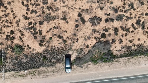 Aerial drone shot looking straight down at a parked car beside the road on the barren Nullarbor Plain, rising vertically over the treeless wilderness