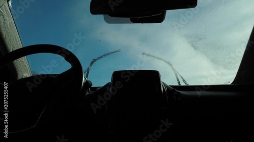 Self-service car wash, person washes windshield with high pressure water jet