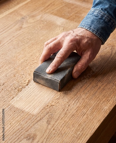 Hand sanding worn oak tabletop with sandpaper macro furniture restoration