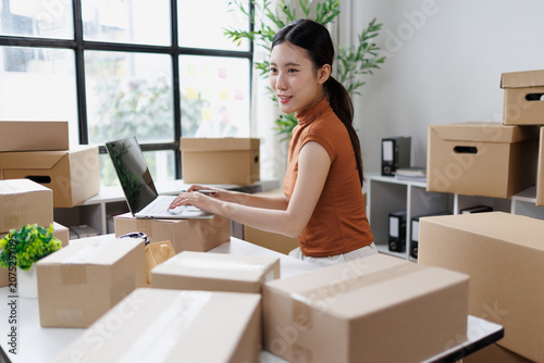 Obraz na płótnie Young asian woman operating an e-commerce store from her home office, confidentl
