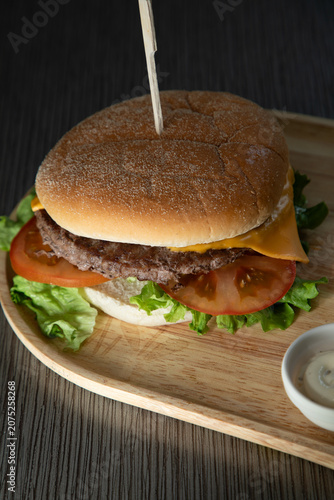 Burger avec salade, tomate et fromage sur une planche en bois
