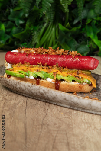 Obraz na plátně Un hot dog avec saucisse, fromage et sauce sur un plateau en bois
