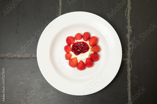 Bild auf Leinwand Dessert avec des fraises et de la confiture au centre sur une assiette blanche