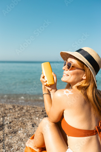 Woman applying sunscreen on beach protecting skin from sun