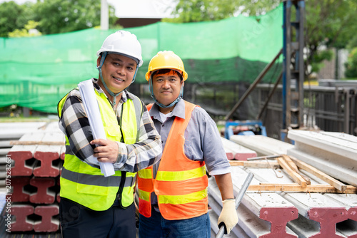 Two confident construction workers, a supervisor and a laborer, smiling for the camera. A portrait of a successful and collaborative building team.