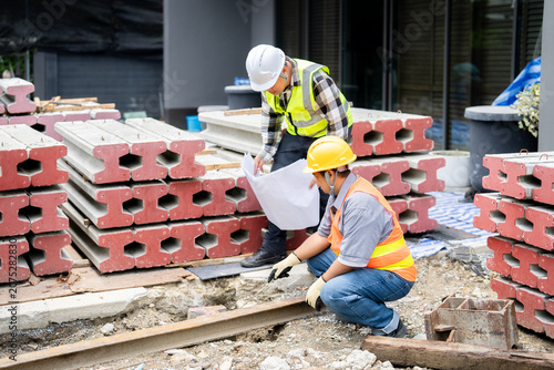 Fotografie Engineer and builder inspecting the groundwork, comparing it to the construction plan and trench alignment on a new home build, ensuring it matches the architectural drawing for quality control