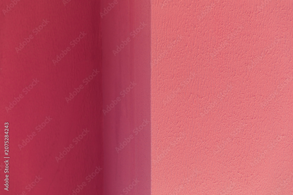 Fototapeta premium A textured wall surface painted in contrasting shades of dark and light pink divided by a vertical line, abstract background, minimalist design, vibrant color contrast.