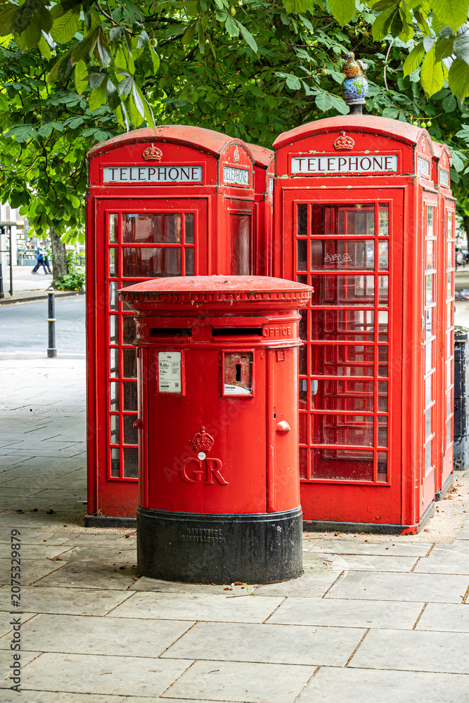 Obraz premium Red phone booths stand beside a postbox