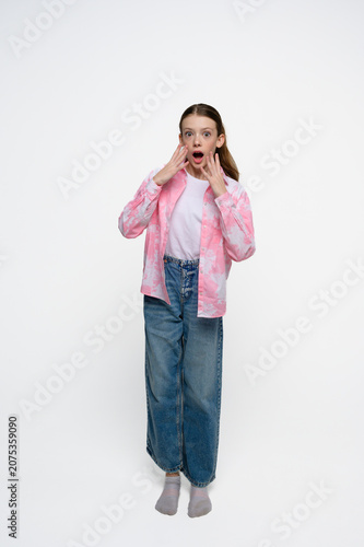 фотографія Surprised teenage girl with wide eyes and open mouth expressing shock, amazement and disbelief