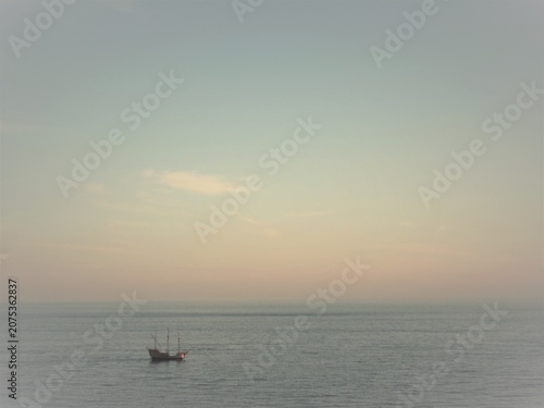 Sailing ship navigating calm ocean under sunset sky