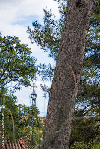Church spire cross peeking through Barcelona trees