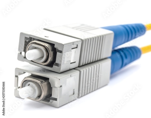 A close-up of two stacked fiber optic connectors with blue and yellow cables