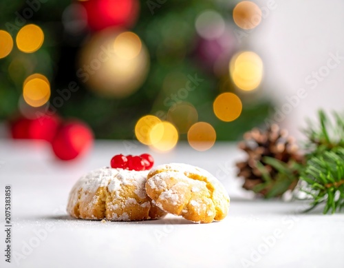 A close-up of two sweet pastries with powdered sugar and red berries on a white surface with a festive background