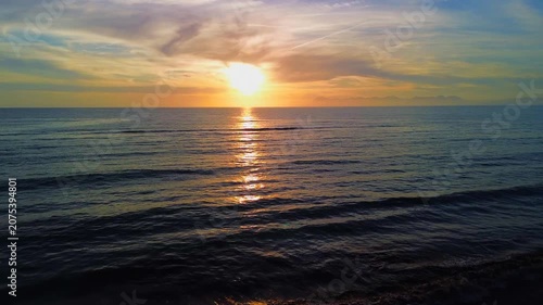 A breathtaking panoramic view of a dramatic golden sunset over the Mediterranean Sea in Agropoli, Cilento coast. The sky is filled with vibrant hues of orange, pink, yellow, and blue clouds, while the