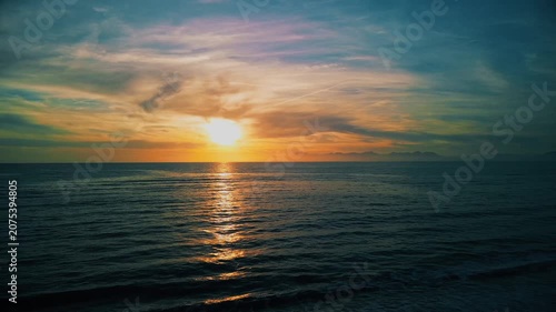 A breathtaking panoramic view of a dramatic golden sunset over the Mediterranean Sea in Agropoli, Cilento coast. The sky is filled with vibrant hues of orange, pink, yellow, and blue clouds, while the