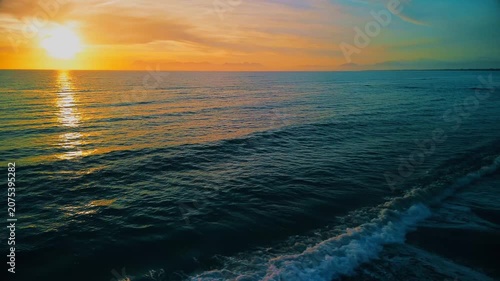 A breathtaking panoramic view of a dramatic golden sunset over the Mediterranean Sea in Agropoli, Cilento coast. The sky is filled with vibrant hues of orange, pink, yellow, and blue clouds, while the