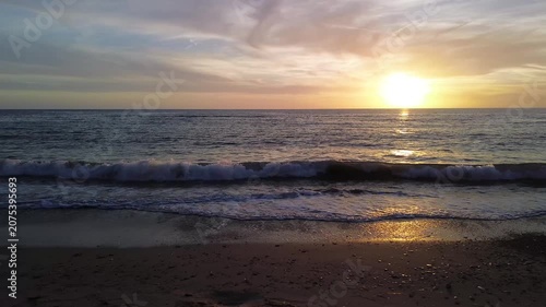 A breathtaking panoramic view of a dramatic golden sunset over the Mediterranean Sea in Agropoli, Cilento coast. The sky is filled with vibrant hues of orange, pink, yellow, and blue clouds, while the
