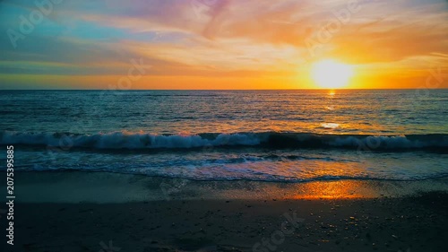 A breathtaking panoramic view of a dramatic golden sunset over the Mediterranean Sea in Agropoli, Cilento coast. The sky is filled with vibrant hues of orange, pink, yellow, and blue clouds, while the