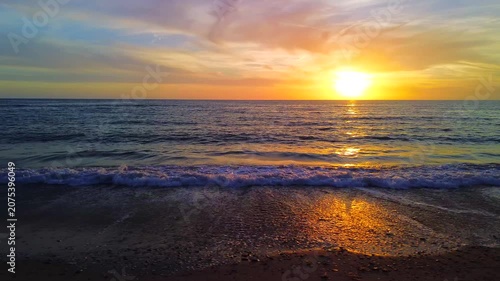 A breathtaking panoramic view of a dramatic golden sunset over the Mediterranean Sea in Agropoli, Cilento coast. The sky is filled with vibrant hues of orange, pink, yellow, and blue clouds, while the