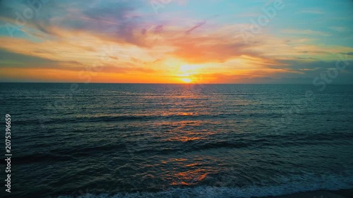 A breathtaking panoramic view of a dramatic golden sunset over the Mediterranean Sea in Agropoli, Cilento coast. The sky is filled with vibrant hues of orange, pink, yellow, and blue clouds, while the