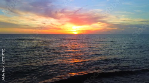 A breathtaking panoramic view of a dramatic golden sunset over the Mediterranean Sea in Agropoli, Cilento coast. The sky is filled with vibrant hues of orange, pink, yellow, and blue clouds, while the