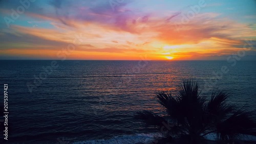 A breathtaking panoramic view of a dramatic golden sunset over the Mediterranean Sea in Agropoli, Cilento coast. The sky is filled with vibrant hues of orange, pink, yellow, and blue clouds, while the