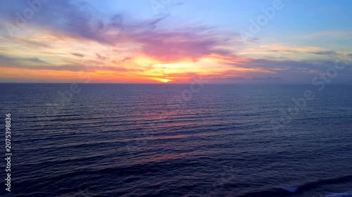 A breathtaking panoramic view of a dramatic golden sunset over the Mediterranean Sea in Agropoli, Cilento coast. The sky is filled with vibrant hues of orange, pink, yellow, and blue clouds, while the
