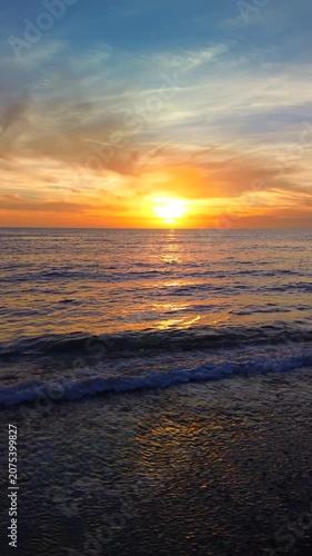 A breathtaking panoramic view of a dramatic golden sunset over the Mediterranean Sea in Agropoli, Cilento coast. The sky is filled with vibrant hues of orange, pink, yellow, and blue clouds, while the