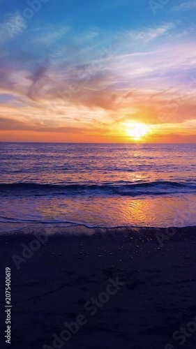 A breathtaking panoramic view of a dramatic golden sunset over the Mediterranean Sea in Agropoli, Cilento coast. The sky is filled with vibrant hues of orange, pink, yellow, and blue clouds, while the