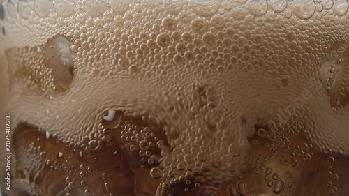 Refreshing Close-Up of Dark Soda Carbonation Fizzing Over Crystal Clear Ice Cubes