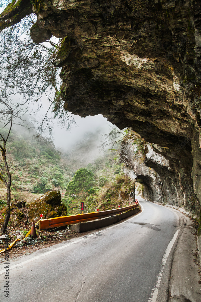 Fototapeta premium Curving mountain road through rock tunnel