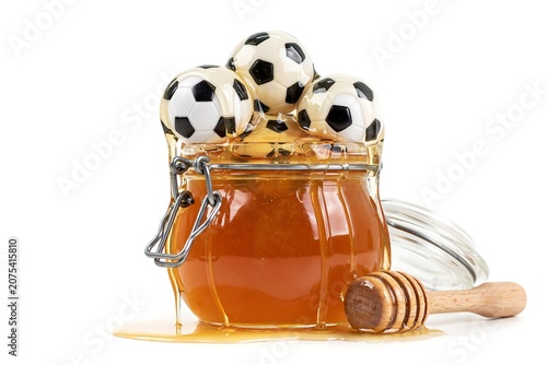 Glass jar with honey and soccer balls on top with dipper  sweet food