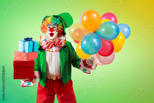 Foto Funny clown with balloons and gifts, entertainers in a suit and wig, with clown whiteface makeup