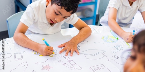 Tableau sur toile Children drawing colorful pictures on a table in a classroom setting