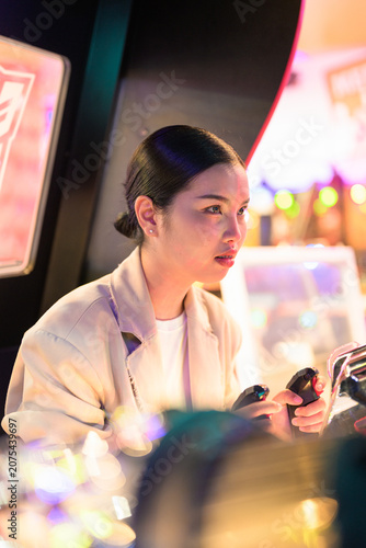 Cuadro en lienzo Young Thai Isan businesswoman holding joysticks at an arcade shooting game conso