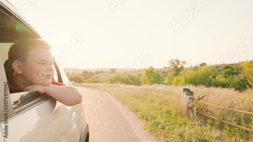 summer vacation by car, opens window breathe fresh countryside air, opens window, happy boy son, driving road, dreamy child smile, road travel, catching wind with his hand from car window, hand wind