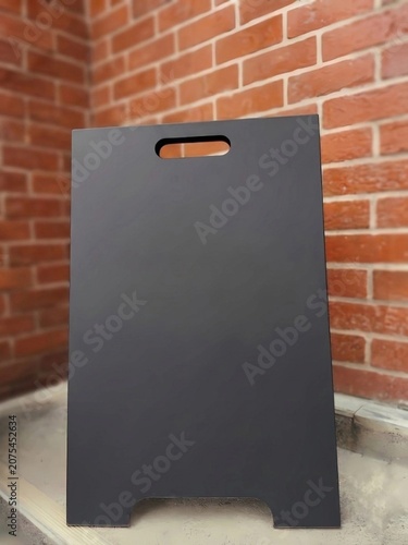 Blank black A-frame sign board mockup standing on brick wall background for advertising promotion message