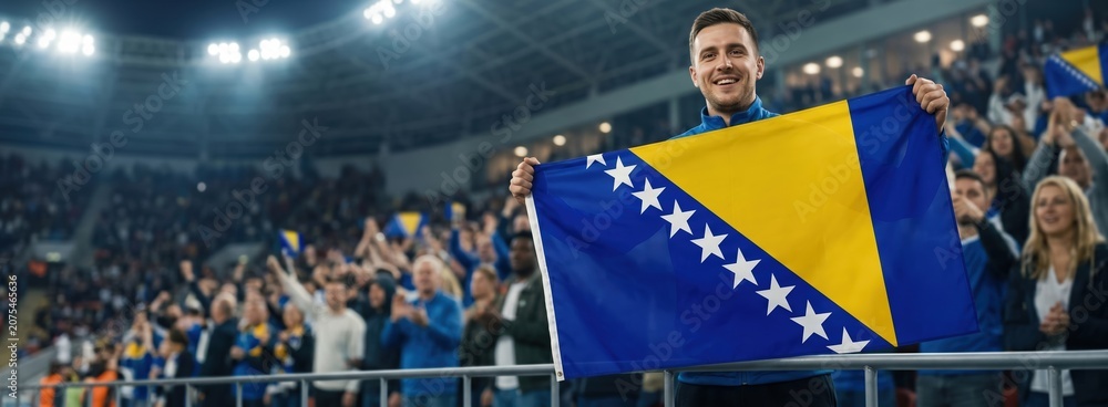 Fototapeta premium Bosnian football fan celebrating with national flag in stadium