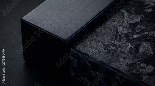 Extreme close-up of dark brushed metal block intersecting with raw carbon fiber texture