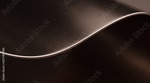 Abstract dark brushed metal background with a smooth sweeping curve and warm edge light