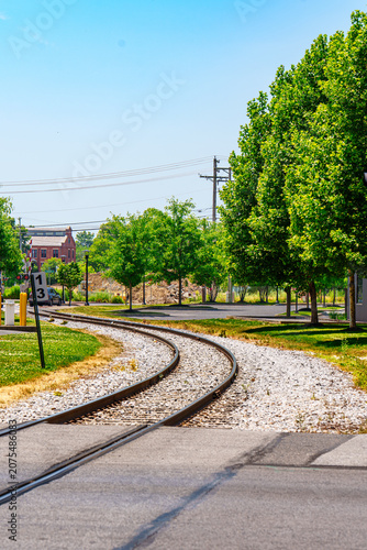 Curving train tracks lined with trees on a sunny day